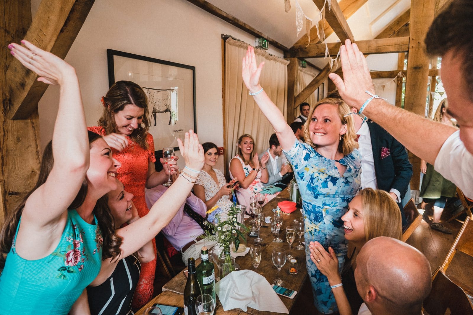 Wedding guests high five in the Oak Barn at Nancarrow