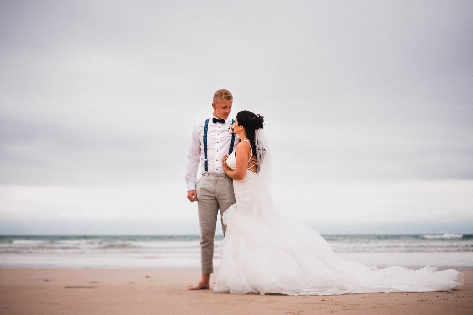 Lusty Glaze Wedding Photography. A portrait of a couple on their wedding day, in front of the ocean at Lusty Glaze Beach.